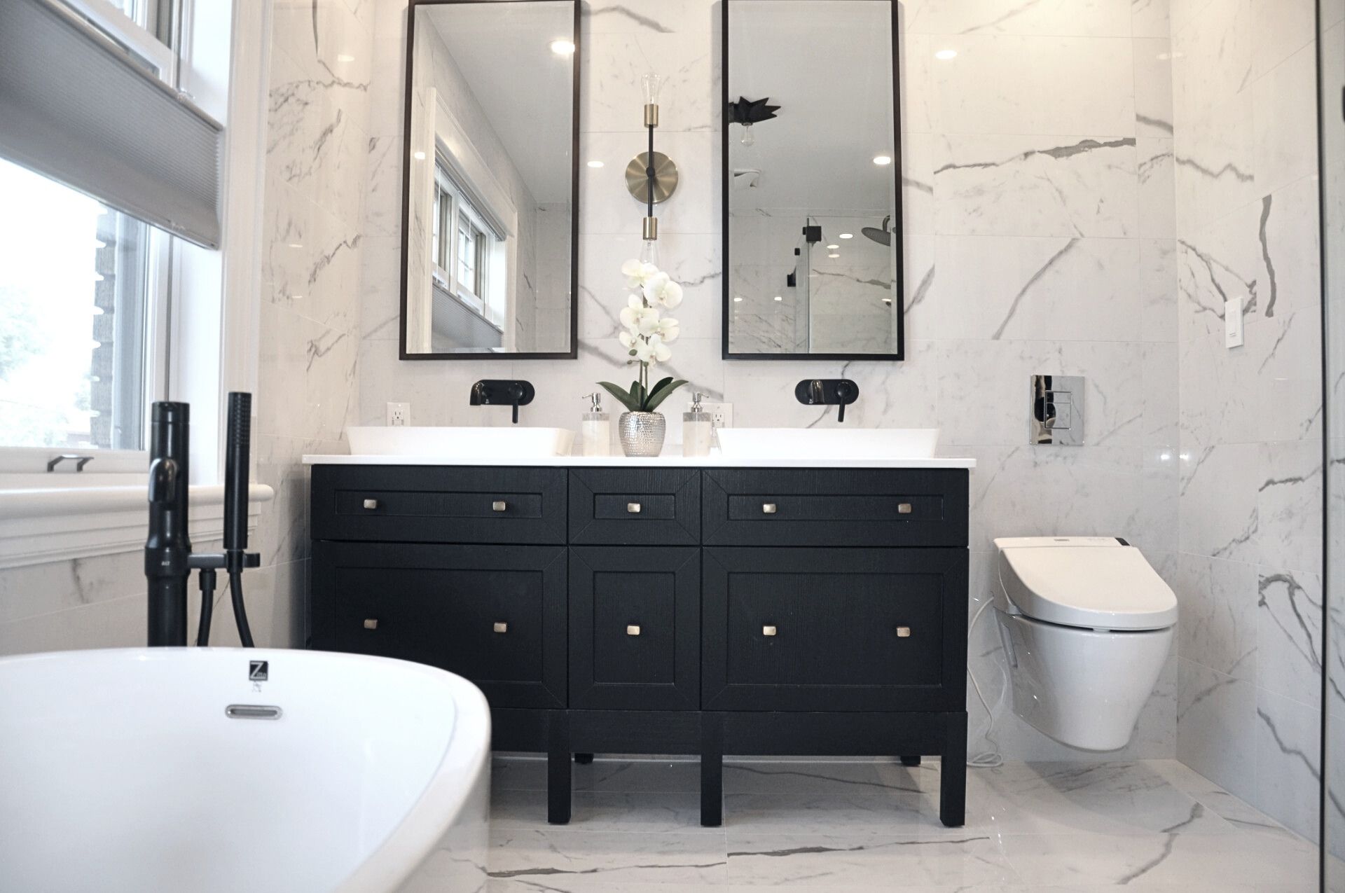 Black and White En-Suite Bathroom Renovation with Double Vanity Black and white en-suite bathroom renovation with black double vanity, marble tile walls, wall-mounted faucets, and freestanding tub
