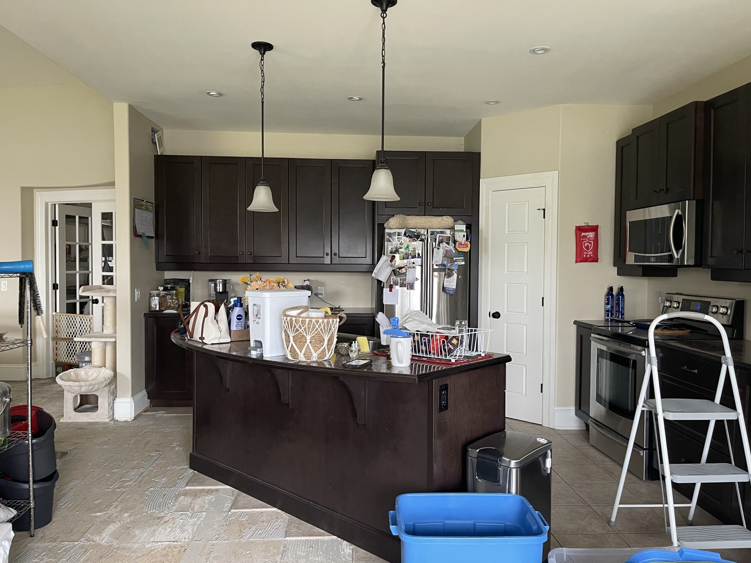 Before renovation kitchen with pendant lighting over island and dark cabinetry throughout
