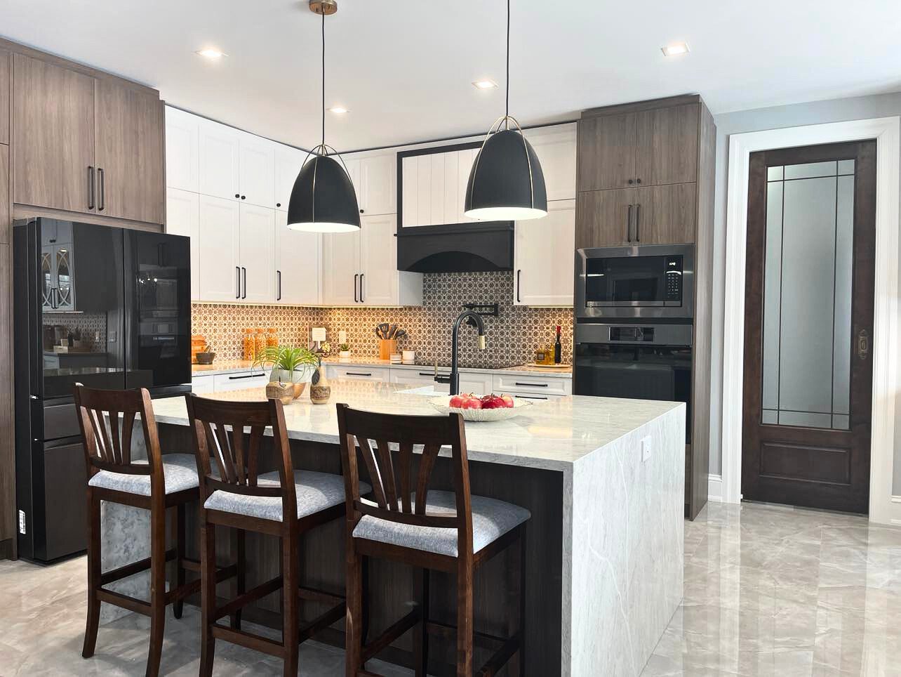 Modern kitchen island with pendant lighting, white cabinetry, quartz waterfall countertop, and dark wood bar stools