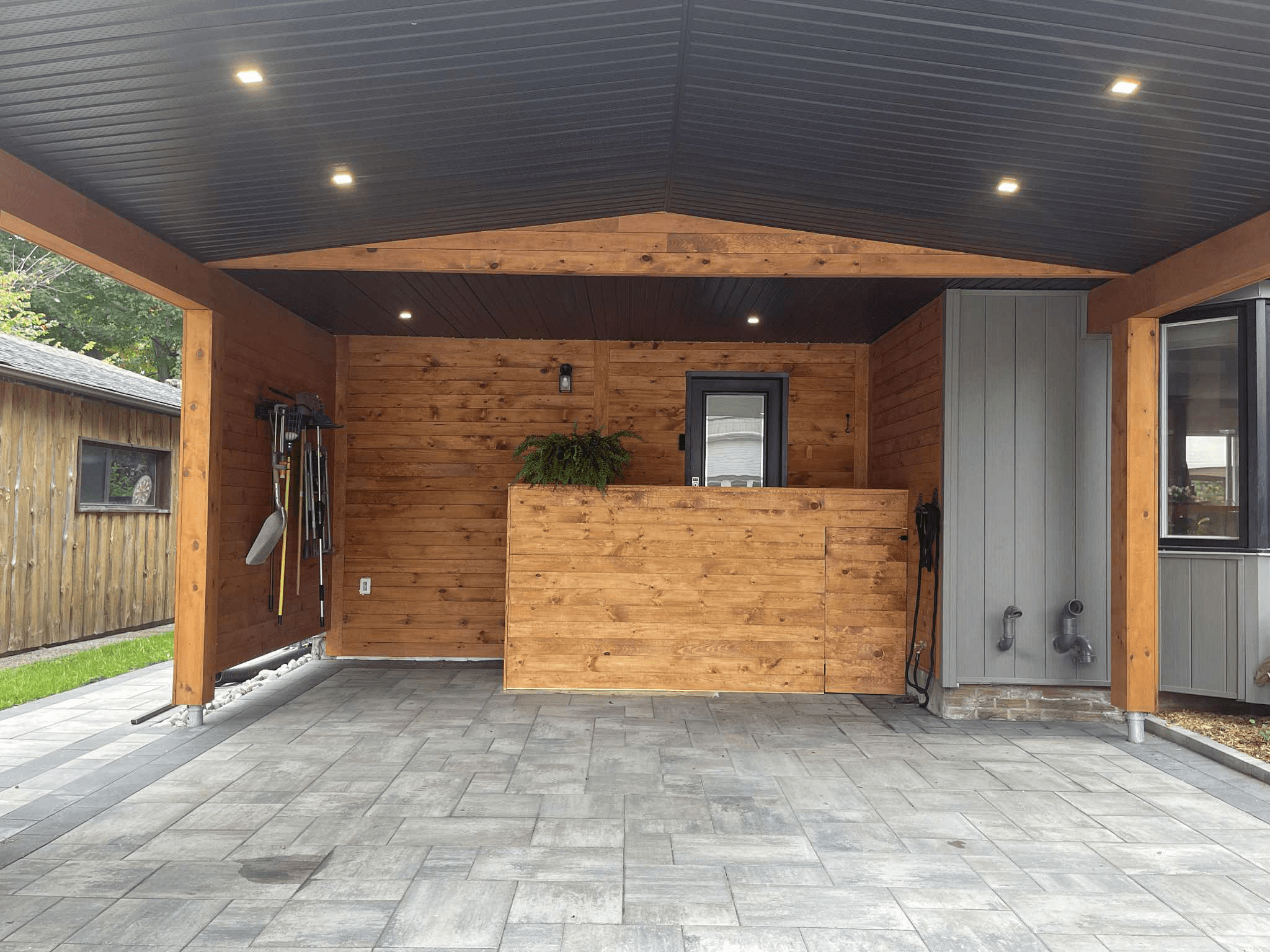 Interior view of cedar carport showing built-in storage wall and finished stone driveway surface