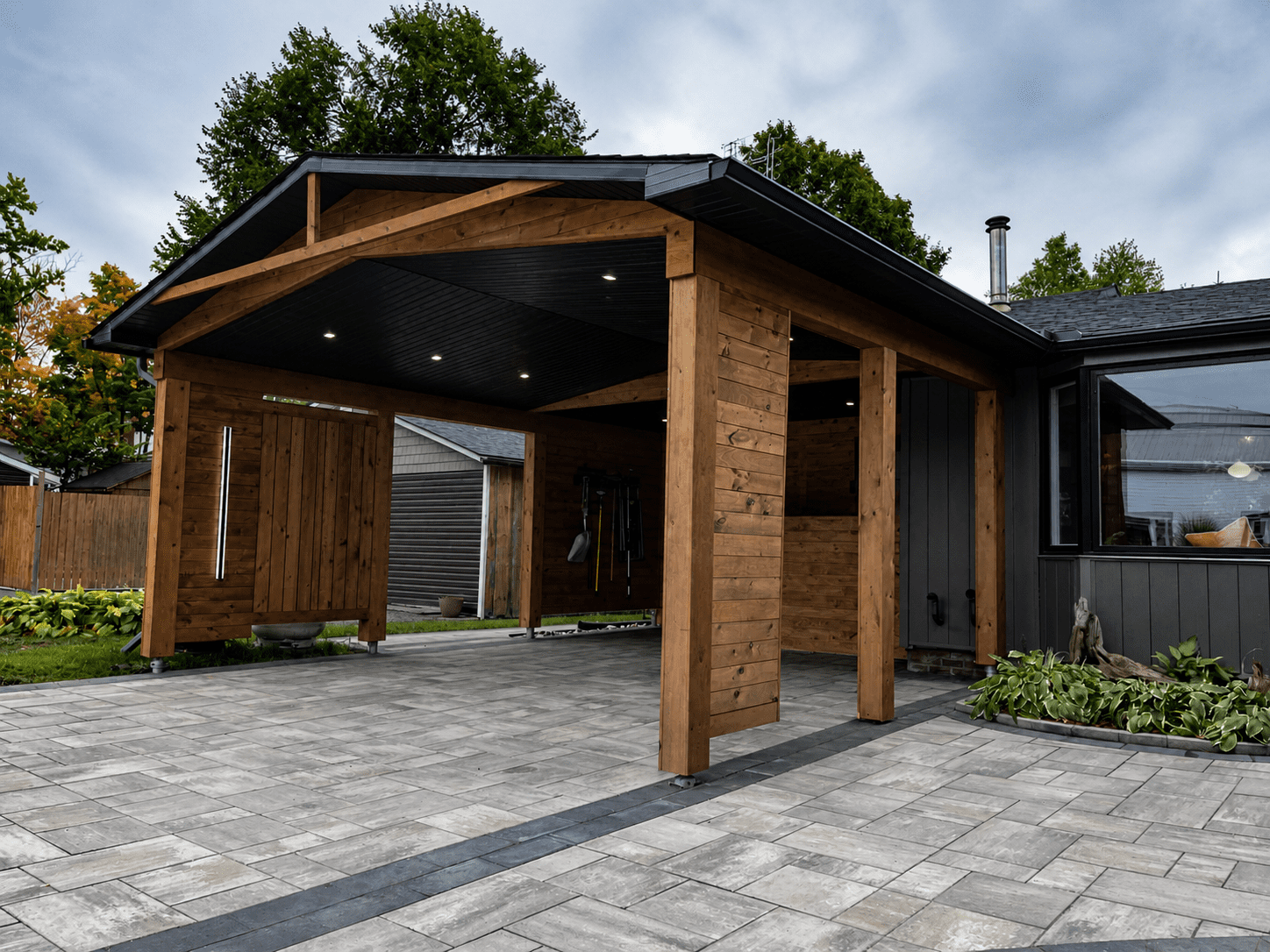 Angled view of custom cedar carport structure with recessed lighting and timber beam detailing