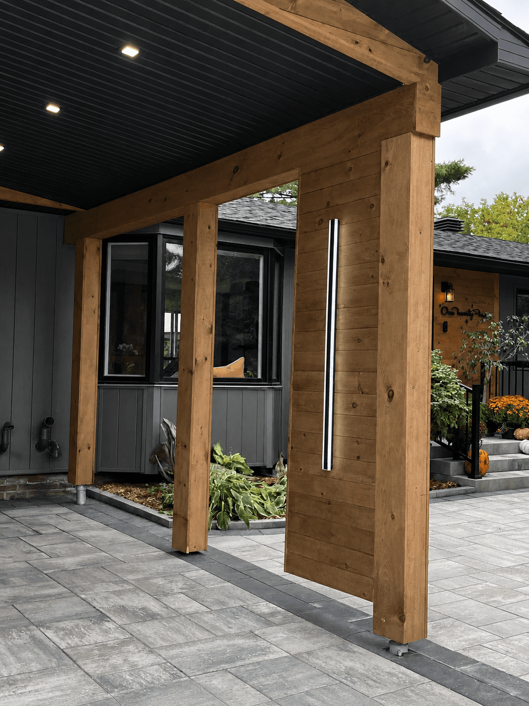 Modern cedar entry partition wall with vertical light feature connecting carport to front entry walkway