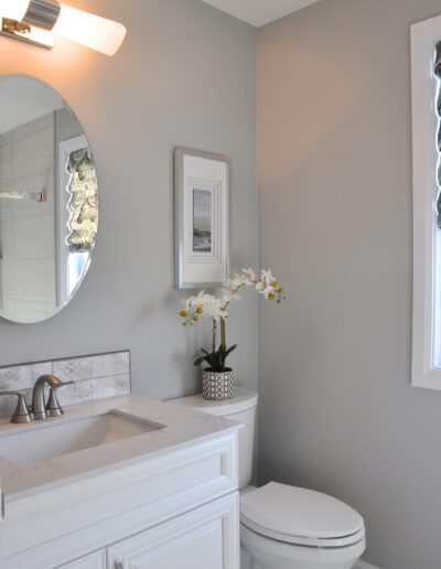 Modern family bathroom in Kemptville with white vanity, framed wall art, and decorative orchid plant