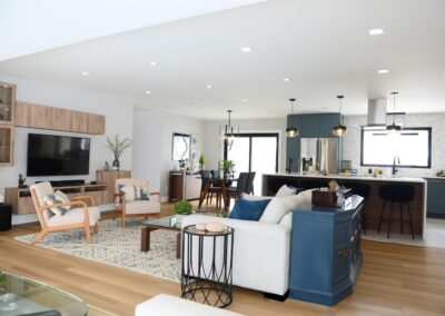 Contemporary living room with feature wall, wood flooring, and open-concept kitchen connection.