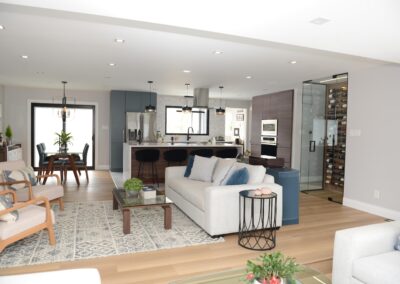 Open-concept living room and kitchen with blue accent cabinetry, contemporary furnishings, and wood flooring.