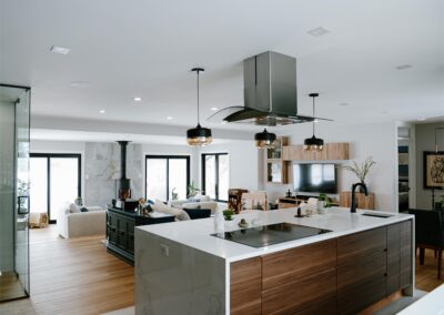 Kitchen and living room open layout with wood accents, modern lighting, and integrated cabinetry.