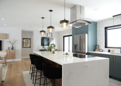 Modern kitchen island with white quartz counter-top, black stools, and pendant lighting.