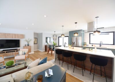 Open-concept view from living room into kitchen with contemporary furnishings and warm wood flooring.