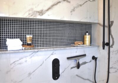 Black mosaic tile shower niche with white grout in a black and white en-suite bathroom