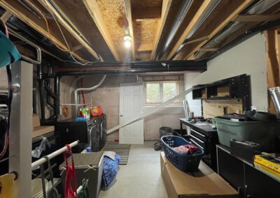Unfinished basement laundry area before renovation with exposed ceiling framing in Kemptville home