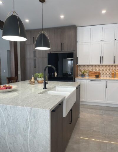 Quartz waterfall kitchen island with black pendant lighting and farmhouse sink