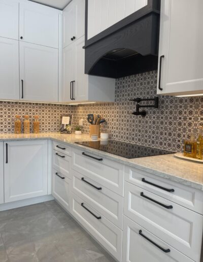 White shaker kitchen drawers with geometric tile backsplash and warm under-cabinet lighting