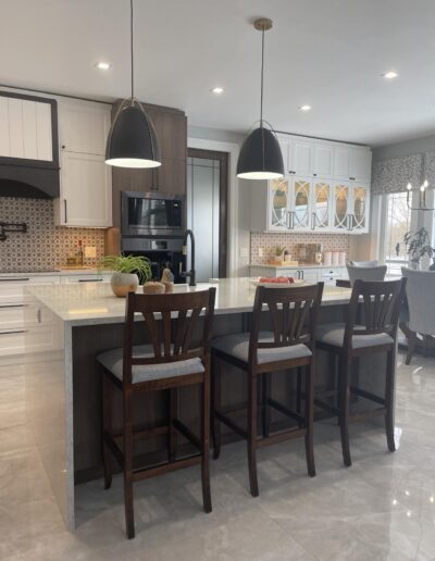 Kitchen island seating with black pendant lighting and white cabinetry in open concept layout