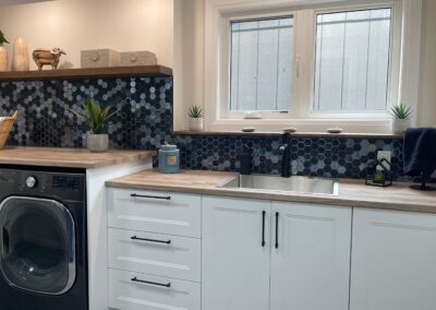 Laundry room sink under window with custom cabinetry and back-splash in Kemptville renovation