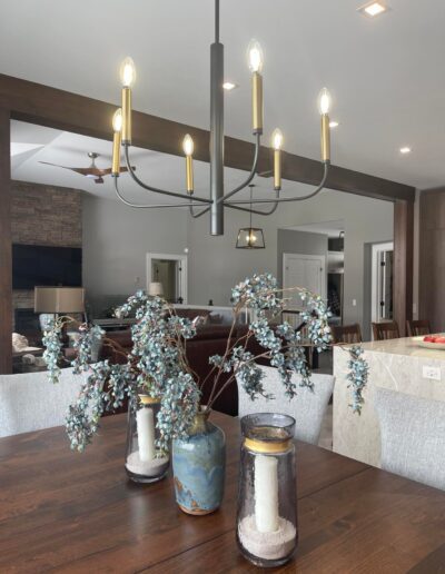 Custom wood beam opening between kitchen and living room with modern chandelier and open concept layout