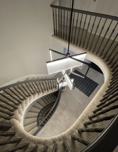 Curved staircase with modern sculptural chandelier in a Kanata entry renovation