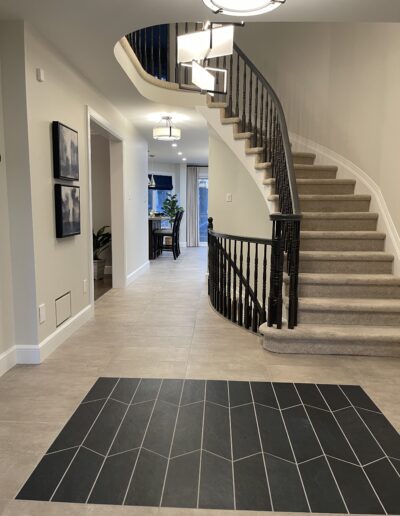 Front entry foyer with curved staircase and tile flooring in a Kanata home renovation