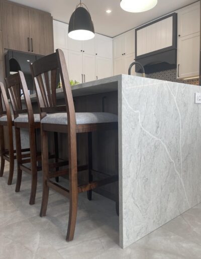 Quartz waterfall kitchen island panel with bar seating and mixed white and wood cabinetry