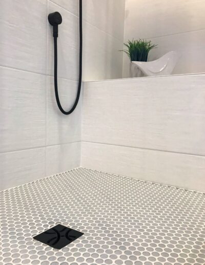 Penny tile shower floor with matte black fixtures in Kemptville bathroom renovation