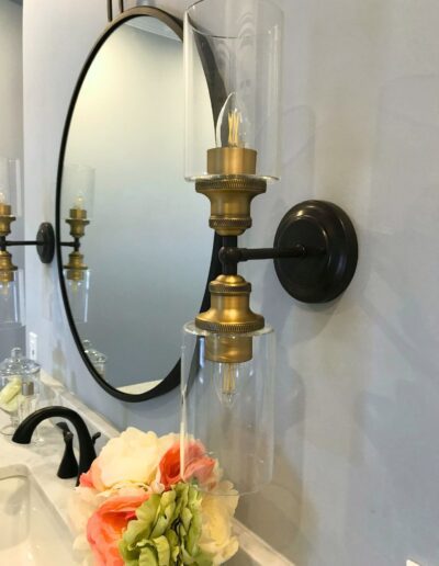 Brass wall sconce beside round mirror in Kemptville bathroom renovation