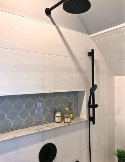 Shower wall with horizontal accent tile band and black fixtures in Kemptville renovation