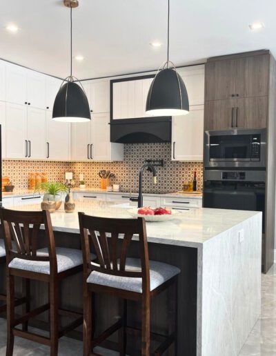 Modern kitchen island with pendant lighting, white cabinetry, quartz waterfall countertop, and dark wood bar stools
