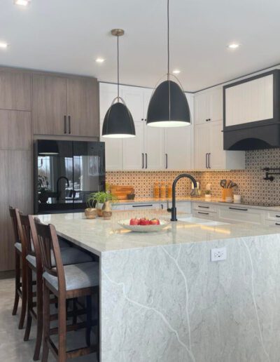 Quartz waterfall kitchen island with black pendant lighting and mixed white and wood cabinetry