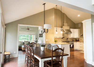 Before photo of a White Lake dining room with vaulted ceilings, wood flooring, large patio doors, traditional furnishings, and partial views into the kitchen and sun room